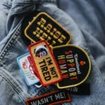 Flat lay of tools needed for how to iron on patches, including an iron, fabric, and patches.