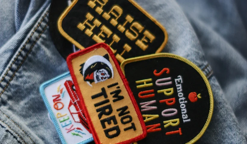 Flat lay of tools needed for how to iron on patches, including an iron, fabric, and patches.