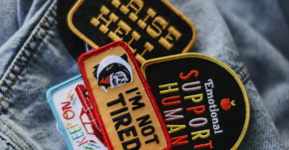 Flat lay of tools needed for how to iron on patches, including an iron, fabric, and patches.