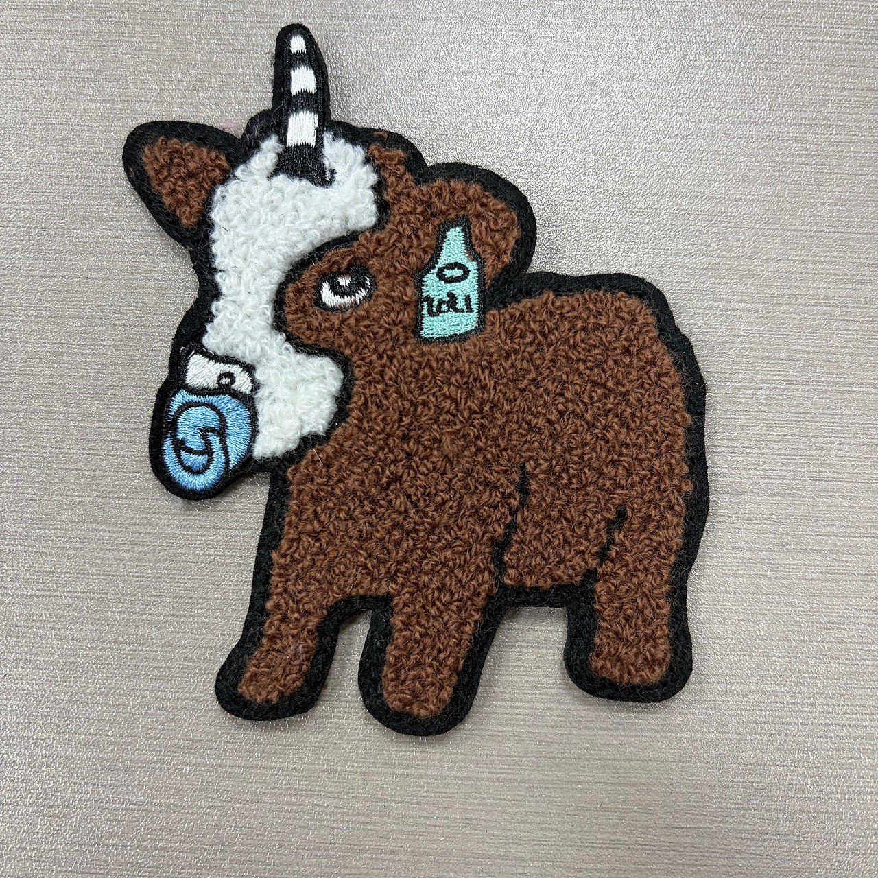 Brown chenille horse patch with black outlines and small flat embroidered accents