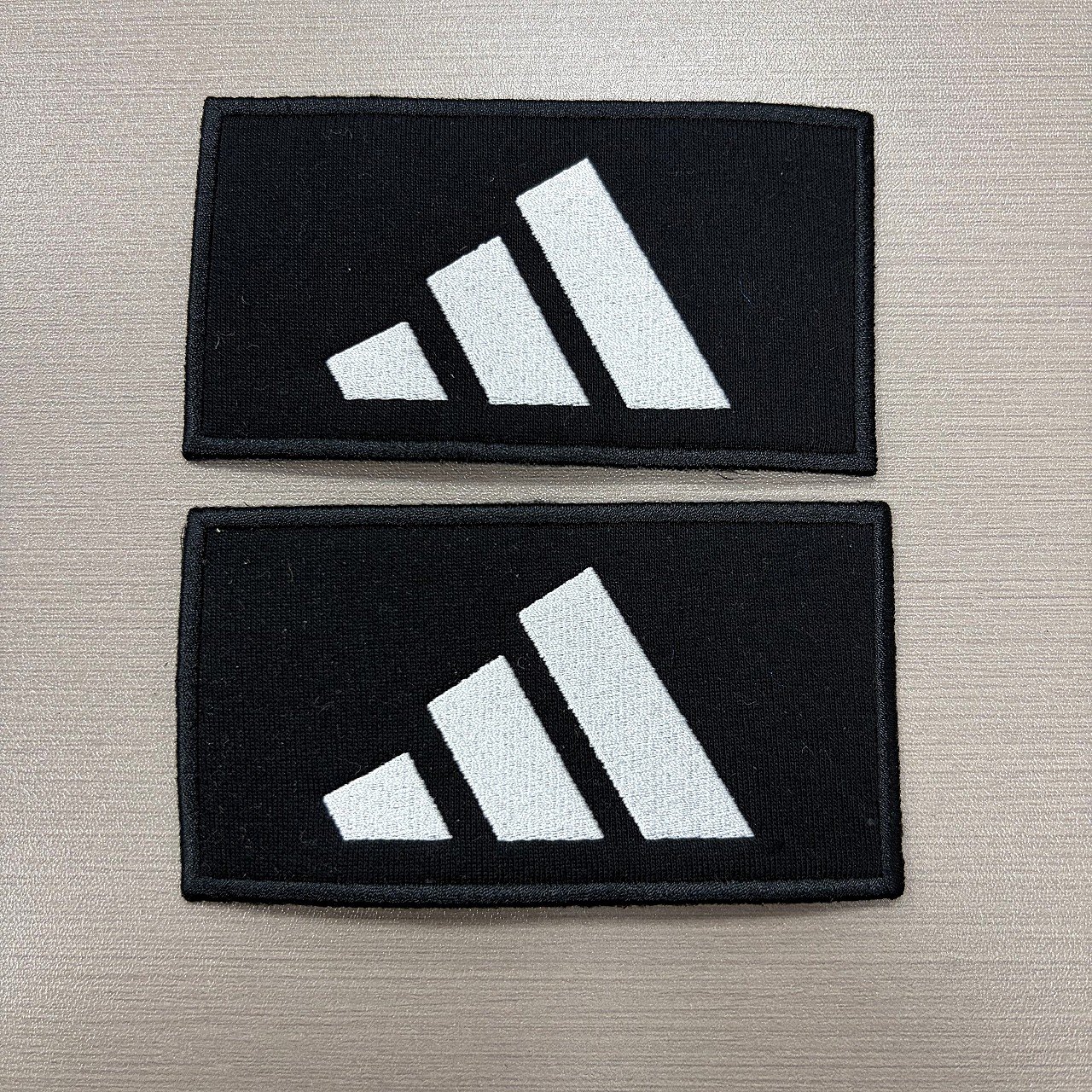 Rectangular black woven patches with white brand marks