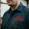 A high-quality embroidered work shirt name patch applied to a mechanic's uniform.