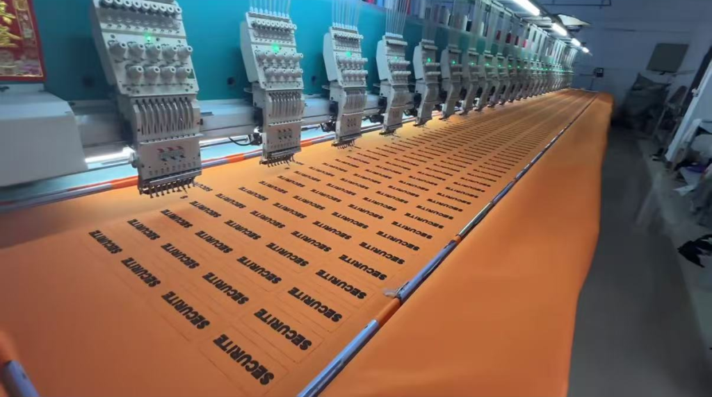 Direct embroidery factory producing bulk custom name patches for B2B corporate uniforms.