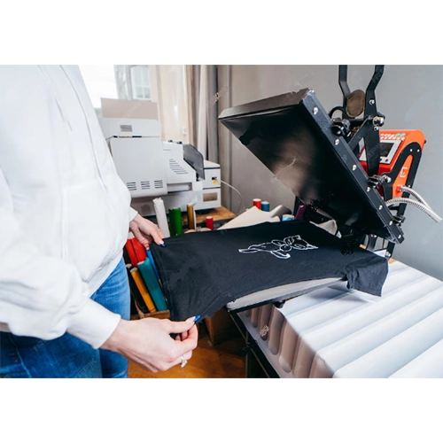 Operator positioning a dark garment on an open heat press