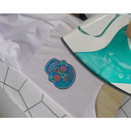 Household iron beside a colourful patch on a white garment