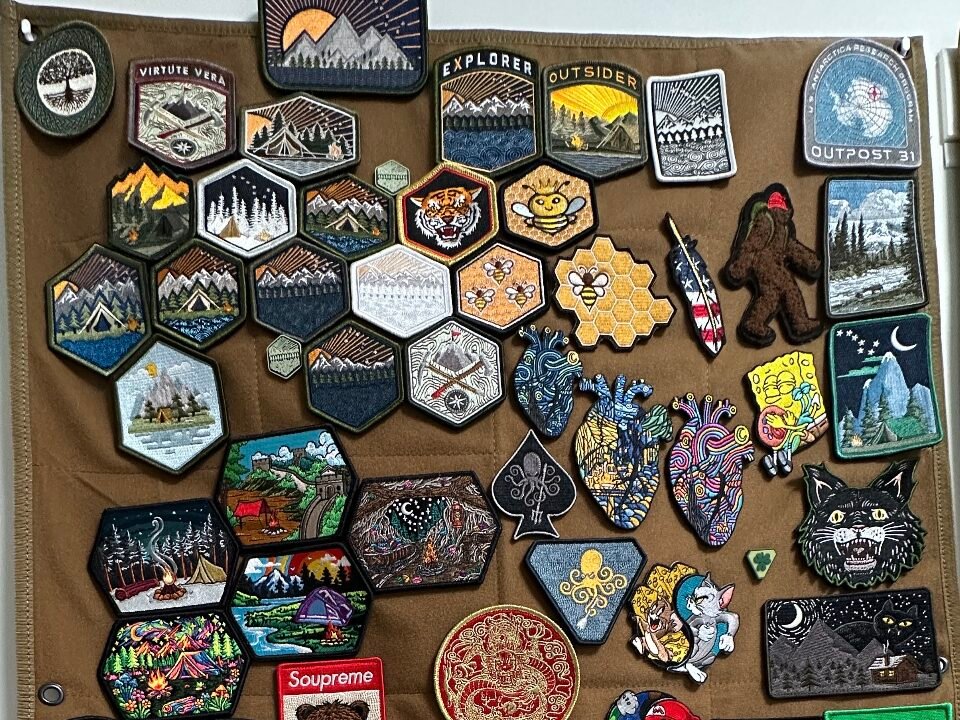 Custom morale patches with mountain, animal, and illustrated designs on a brown fabric display board