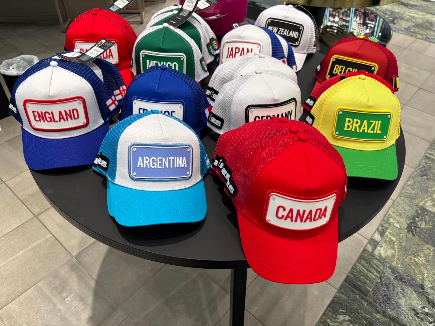 Custom patch hats with colorful mesh backs and rectangular country-name patches displayed on a table