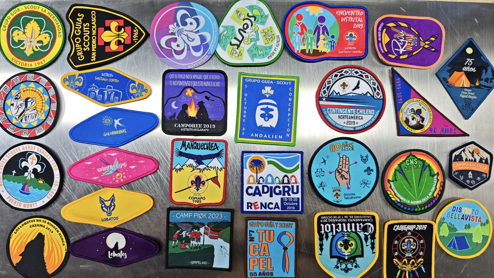 Custom scout patches in round, shield and event designs displayed on a table
