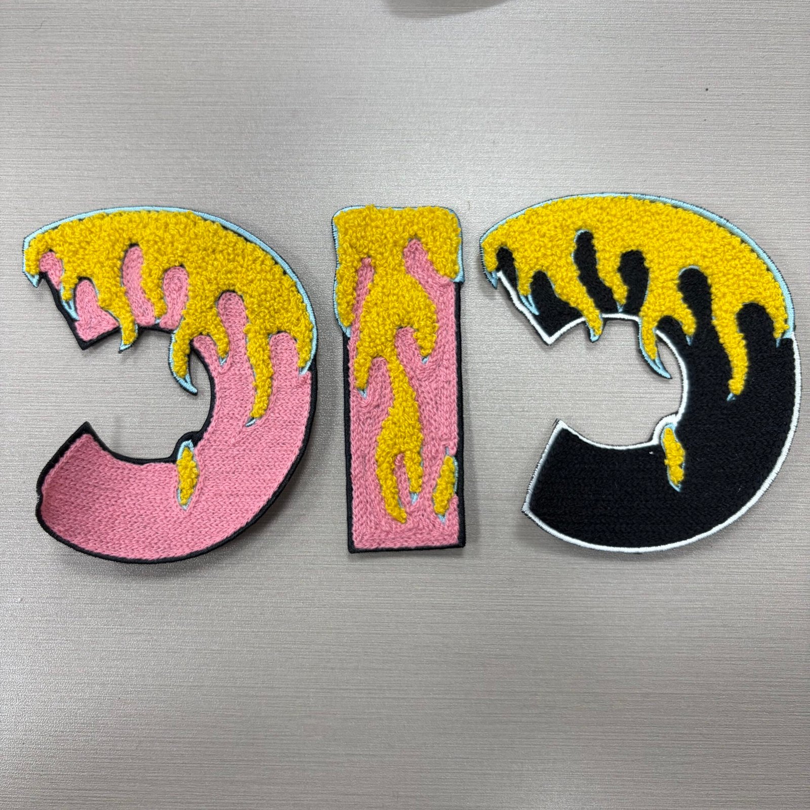 Pink and black chenille letter shapes with yellow dripping color details