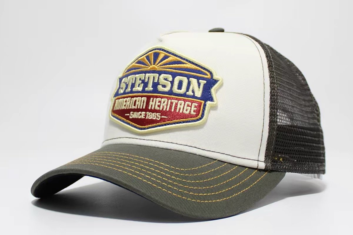 Cream-front trucker hat with dark mesh, olive brim and a multicolor shaped badge