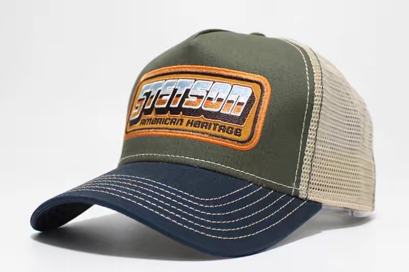 Olive trucker hat with navy brim, beige mesh and an orange-bordered rectangular patch