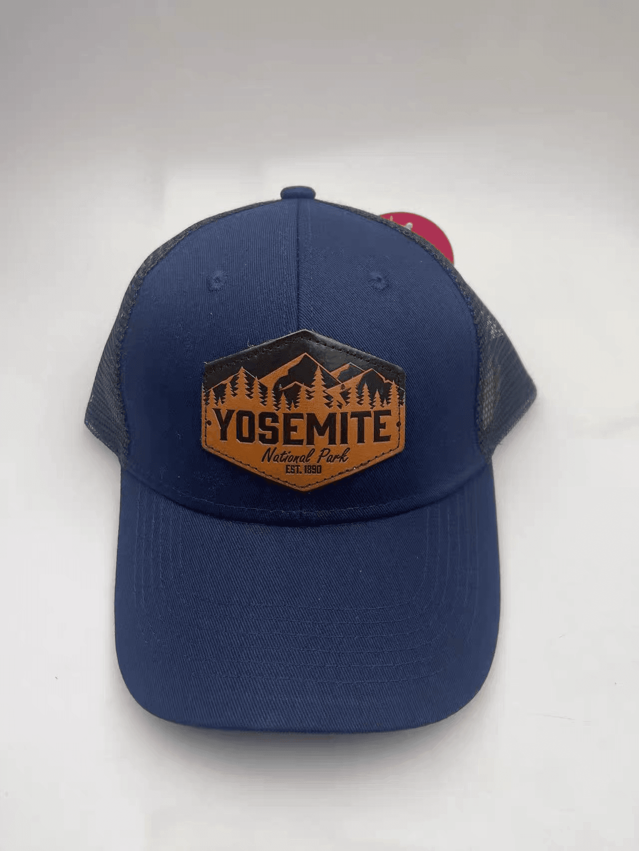 Navy mesh-back trucker hat with a shaped mountain-design leather patch on the front.