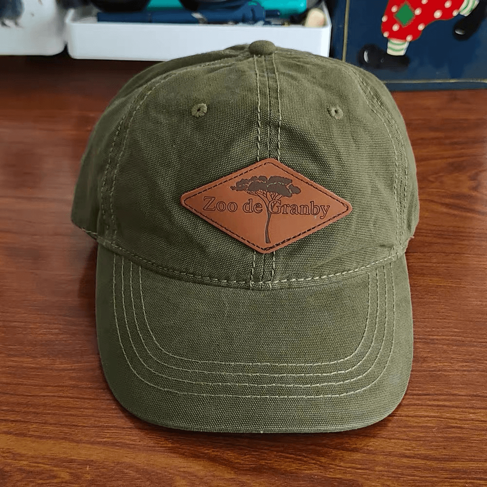 Olive cap with a diamond-shaped brown leather patch stitched across the front seam.