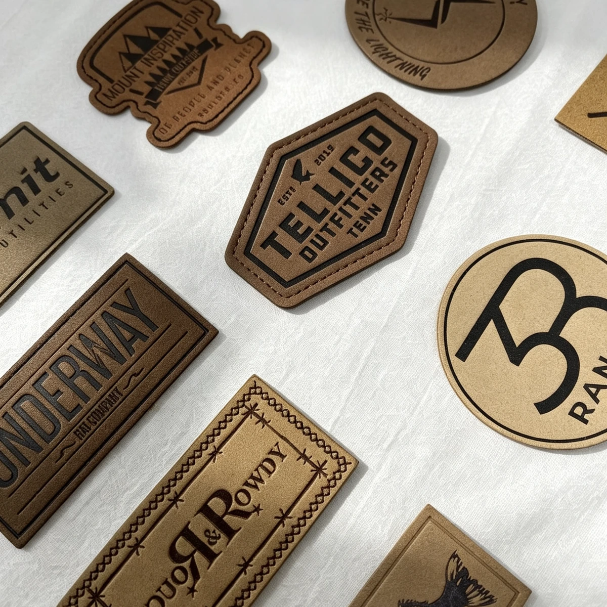 Brown leather logo patches in rectangular, round and custom shapes on white fabric