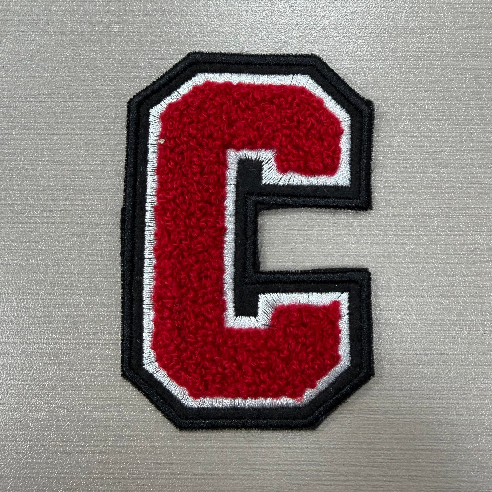 Red chenille C with white stitched outline and black felt border
