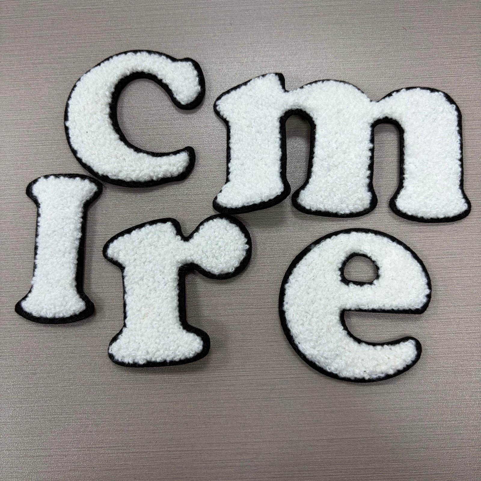 White chenille C, m, I, r and e letter pieces with black outlines