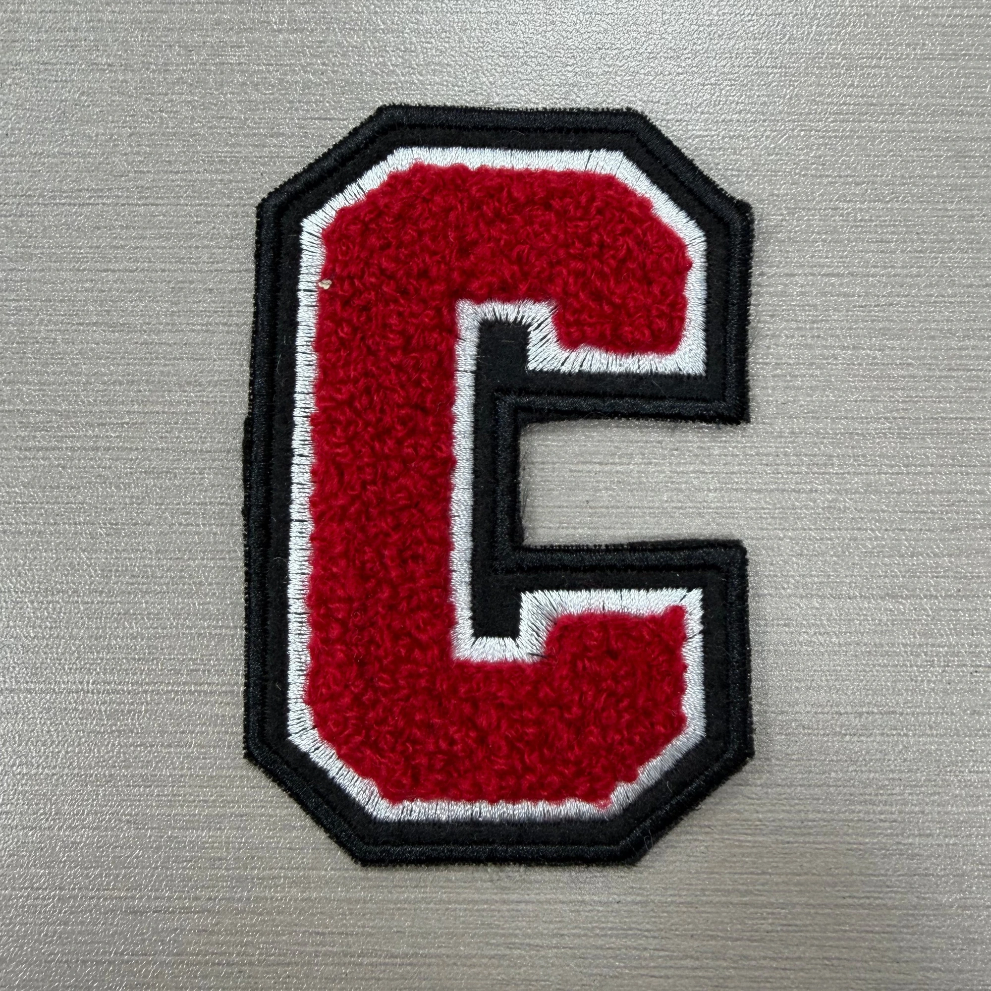 A red chenille letter C finished with white and black satin-stitch embroidered borders.